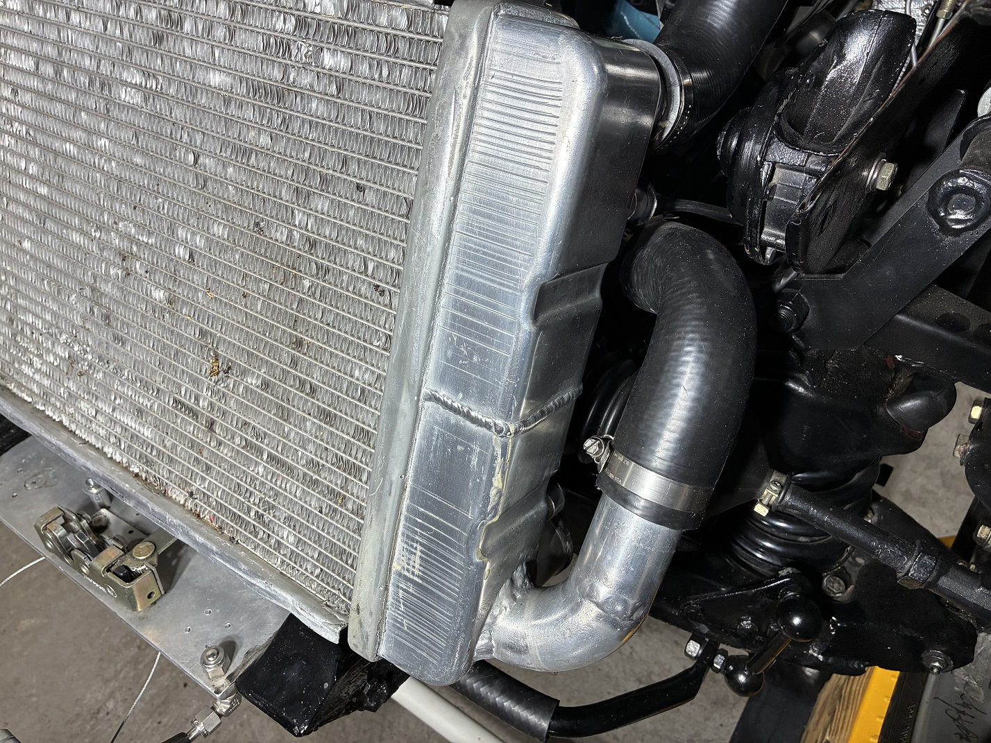 Bottom hose connection to radiator via custom-welded side tubing outlet.